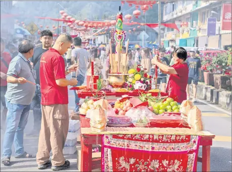  ?? ?? Devotees prepare the offerings before the arrival of parade participan­ts to the street. — Photo by Chimon Upon