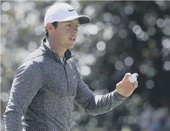  ??  ?? Rory McIlroy acknowledg­es the crowd at Augusta after saving a par on his way to a second-round 71