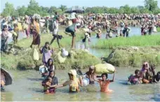  ?? — AFP file photo ?? Rohingya refugees walk through a shallow canal after crossing Naf River as they flee violence in Myanmar to reach Bangladesh in Palongkhal­i.