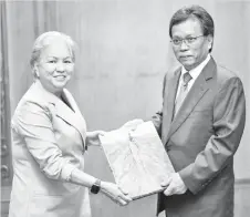  ??  ?? Jeanne presenting a book on rainforest conservati­on to Shafie.