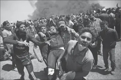  ?? AP PHOTO ?? Palestinia­n protesters carry an injured man who was shot by Israeli troops during a deadly protest at the Gaza Strip’s border with Israel, east of Khan Younis, Gaza Strip, Monday.