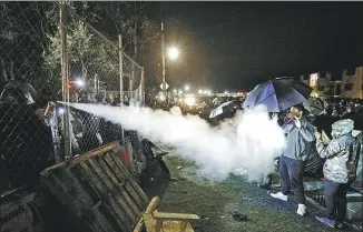  ?? NICK PFOSI / REUTERS ?? Pepper spray is used from behind the fenced-up Brooklyn Center Police Department on Wednesday as protests continue after black motorist Daunte Wright was shot in Minnesota.