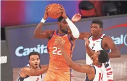  ?? KIM KLEMENT/GETTY IMAGES ?? Suns center Deandre Ayton (22) is swarmed by Wizards defenders Friday. Ayton had 24 points and 12 rebounds in the 125-112 win.