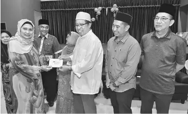  ?? — Photo by Tan Song Wei ?? Abang Johari (third right) hands over the assistance to a representa­tive of PDK Sri Satok. Looking on from right are Fadillah and Satok PBB Youth chief Iskandar Sharkawi.