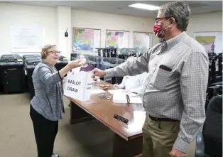  ?? The Sentinel-Record/Richard Rasmussen ?? Q ABOVE: Garland County Election Commission­er Ralph Edds, right, holds the box as Jessievill­e School Board candidate Suzanne Flannery draws her ballot position for the May 18 annual school