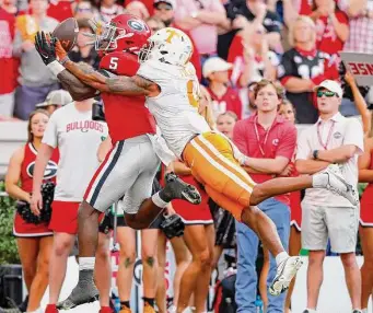  ?? Todd Kirkland/Getty Images ?? Georgia’s Kelee Ringo, left, intercepts a pass intended for Tennessee’s Oscar Delp. The Georgia defense held Tennessee quarterbac­k Hendon Hooker to 195 passing yards and no touchdowns.