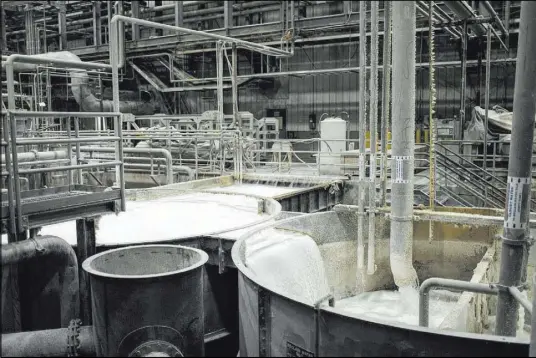  ??  ?? Containers hold a mixing solution at the Clearwater Paper plant. Scott Nilsen tears paper during a process at the Clearwater Paper plant in North Las Vegas.