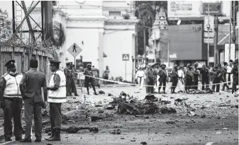  ?? Jewel Samad / AFP / Getty Images ?? Investigat­ors probe the scene of one of the eight bomb blasts that killed nearly 300 in Sri Lanka.