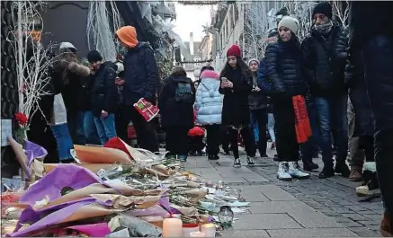  ??  ?? Les habitants viennent se recueillir en hommage aux victimes de l’attentat dans la rue des Orfèvres à Strasbourg.