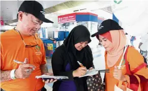  ??  ?? Doing good: Low (left) and a volunteer explaining about organ donation to a commuter at the Bangsar LRT station.