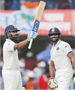  ?? — AP ?? INDORE: Indian batsman Rohit Sharma, left, celebrates his half century with Ravindra Jadeja during the second day of the third test cricket match between India and New Zealand in Indore, India, yesterday.