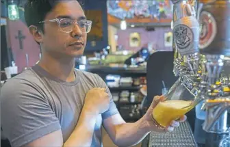  ?? Lake Fong/Post-Gazette ?? Bartender Sam Amity pours an Plataversa­ry IPA at Mad Mex in Shadyside. First released as Dos Decadas for the Mad Mex 20th Anniversar­y, it's brewed exclusivel­y for the restaurant by Fat Head’s in Ohio.