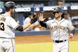  ?? MARTA LAVANDIER/AP ?? The Giants’ Austin Slater (13) congratula­tes Tommy La Stella after he scores a run in the third inning Sunday against the Marlins in Miami.