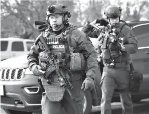  ?? Associated Press ?? ■ Police officers armed with rifles stage Friday near a commercial building where an active shooter was reported in the 600 block of Archer Avenue in Aurora, Ill.