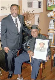  ?? / Doug Walker ?? Left: Norris K. Allen Sr., left, and J.L. Vaughn Sr. with a photo of Vaughn when he was the first African-American principal of an integrated school in Rome, the old Johnson Elementary School. The photo is part of a series of items Allen has donated to the Rome Area History Museum.