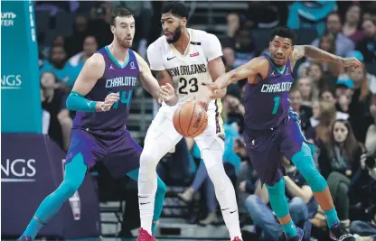  ?? AP ?? Malik Monk, a la derecha, de los Hornets, recupera el balón ante Anthony Davis, de New Orleans, mientras Frank Kaminsky observa en la primera mitad del partido de anoche en el baloncesto de la NBA,