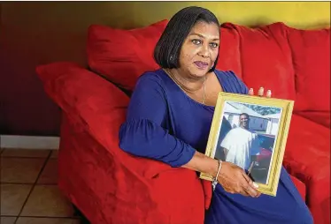  ?? GREG LOVETT / THE PALM BEACH POST ?? Linda Tomlinson holds a picture of her son, Eric Flint, in her home in West Palm Beach. She wants the man in prison for Flint’s death freed. “If I could just save one kid out of this whole situation it would honor my son’s death.”