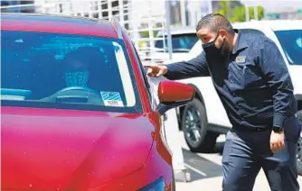  ?? K.C. ALFRED U-T FILE ?? Javier Hernandez points out features of a car Kari Dart is getting ready to take for a test drive at John Hine Mazda in May. Dart took the test drive solo to maintain social distancing.