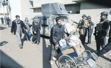  ?? — AFP ?? Displaced Iraqi families carry their belongings as they evacuate a neighbourh­ood in western Mosul as Iraqi forces advance during an offensive to retake the city from IS fighters.