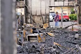  ?? AP PHOTO/MORRY GASH ?? A woman looks at a burned out building Tuesday after earlier protests in Kenosha, Wis.