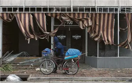  ?? Godofredo A. Vásquez / Staff file photo ?? A man pushes his bicycle Aug. 27 near a store in Lake Charles, La., damaged during Hurricane Laura, which also struck East Texas. Stronger hurricanes are expected to become more common as Earth warms. Laura made landfall as a Category 4 storm.