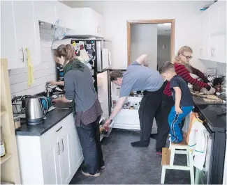  ??  ?? Megan Brydie, left, Patrick Caldicott and Anika Vervecken prepare dinner while Vervecken’s fouryear-old son, Laelo, climbs a chair for a better view of the activities.