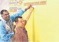  ??  ?? Sutaghani (right) and Rethnasamy put their pledge cards on the board.