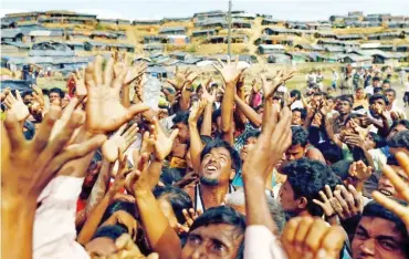  ?? Photo: Reuters ?? Rohingya refugees receive aid at the Balukhali camp in Cox’s Bazar, Bangladesh yesterday