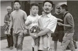  ?? Gerry Shih / Associated Press ?? This image from video shows Chinese labor activists Hua Haifeng, center, carrying his son Bobo, and Li Zhao, second from left, leaving a police station.