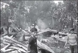  ?? JOHN UNSON ?? Residents stand near razed houses in Barangay Tubigan in Maluso, Basilan following an attack by Abu Sayyaf bandits yesterday.