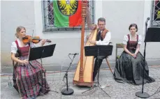  ?? FOTO: TOBIAS SCHUMACHER ?? Johannes Rahn an der Harfe und seine beiden Mitmusiker­innen bei der „Isnyer Stubenmusi­k“im Hinterhof des Isnyer Rathauses beim Dankeschön-Empfang der Stadt für Sponsoren und Helfer beim Kinderfest, Rettungskr­äfte und Freunde aus den Partnerstä­tten...