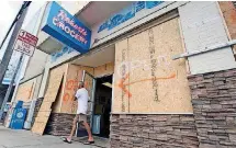  ?? [AP PHOTO] ?? A man walks out of the boarded up Robert’s Grocery in Wrightsvil­le Beach, N.C., in preparatio­n for Hurricane Florence. Though it’s far from clear how much economic havoc Hurricane Florence will inflict on the southeaste­rn coast, from South Carolina through Virginia, the damage won’t be easily or quickly overcome. In those states, critically important industries like tourism and agricultur­e are sure to suffer. “These storms can be very disruptive to regional economies, and it takes time for them to recover,” said Ryan Sweet, an economist at Moody’s Analytics.