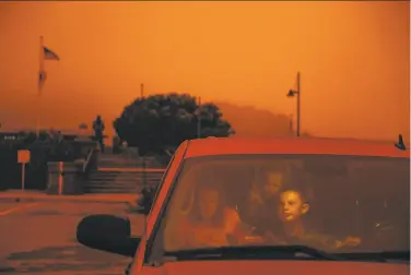  ?? Gabrielle Lurie / The Chronicle ?? Lisa Trythall of Salt Lake City makes sandwiches for her children as they sit in their car in Sausalito during a road trip on Wednesday. Her son, Luke, looks around at the orange sky while he waits.