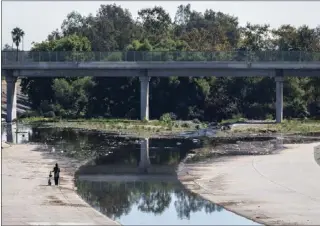  ?? HANS GUTKNECHT — STAFF PHOTOGRAPH­ER ?? On the waterfront: A person walks along the Los Angeles River in Encino last week. Nighttime temperatur­es will drop into the 50s this week, giving some areas a first taste of fall-like weather.