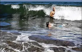  ?? JAMES WOOLDRIDGE / THE PALM BEACH POST ?? Determined not to let red tide stop them from enjoying the ocean on their vacation, Luke Dillon (front) and his father, Eddie, of Kentucky swim off Lake Worth Beach in Lake Worth, Fla., on Friday.