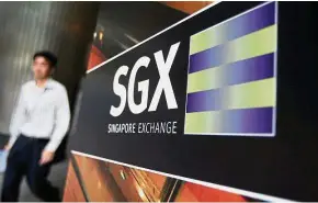  ??  ?? OTC deals: An office worker walking past the SGX logo outside its premises in Singapore. More than 85% of futures transactio­ns on the SGX are done over the counter. — Reuters