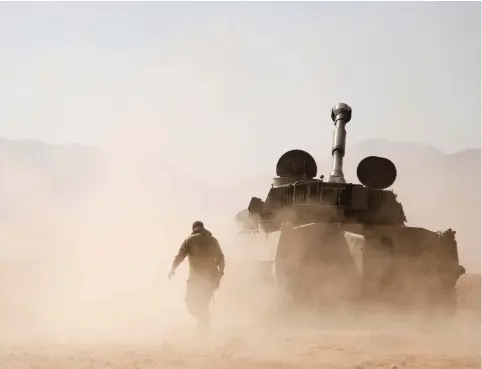  ??  ?? HEZBOLLAH FIGHTERS walk near a tank in Western Qalamoun, Syria on Wednesday