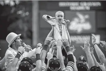  ?? STEPHEN B. MORTON/AP PHOTO ?? Molly Knutson holds her baby James Knutson high above the players as the Savannah Bananas present the Banana Baby to the crowd while playing the theme song from the movie “Lion King” over the public address system on June 11 in Savannah, Ga.