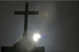  ?? HASSAN AMMAR/AP FILE ?? A partial solar eclipse is seen behind a cross on the steeple of the St. George church in Beirut, Lebanon, in 2020. Throughout history, solar eclipses have had profound impact on adherents of various religions around the world.