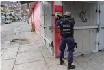  ?? —AFP ?? CARACAS: A member of the Bolivarian National Police aims at a possible target after clashes with alleged members of a criminal gang in the Cota 905 neighborho­od on Friday.