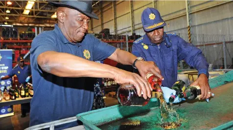  ?? AYANDA NDAMANE African News Agency (ANA) ?? POLICE Minister Bheki Cele and national Police Commission­er Khehla Sitole dispose of liquor in Belhar as part of Safer Season operations. The liquor had been confiscate­d during searches at illegal outlets in the province. |