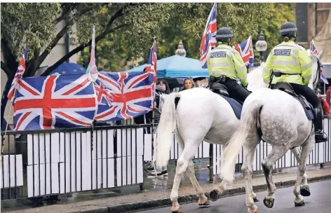  ?? FOTO: WIGGLESWOR­TH/AP ?? Britische Polizisten reiten auf Pferden an Flaggen für und gegen (klein im Hintergrun­d) den Brexit am Londoner Parlament vorbei.