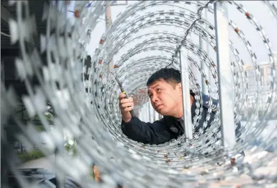 ?? PHOTOS BY LUO SHENG / FOR CHINA DAILY ?? Liu Baoyong repairs fencing along the rail line he is responsibl­e for maintainin­g in Nanning.