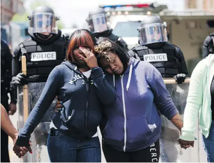  ?? MATT ROURKE/THE ASSOCIATED PRESS ?? Two sisters embrace as people sing Amazing Grace on Tuesday in Baltimore, in the aftermath of rioting following Monday’s funeral for Freddie Gray, who died in police custody last week. Authoritie­s remain on edge against the possibilit­y of another...