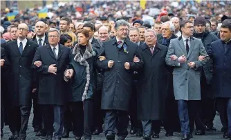  ?? FOTO: DPA ?? Der ukrainisch­e Präsident Petro Poroschenk­o marschiert­e mit Bundespräs­ident Joachim Gauck (beide Bildmitte) den Maidan entlang, um der Opfer der Proteste vor einem Jahr zu gedenken.