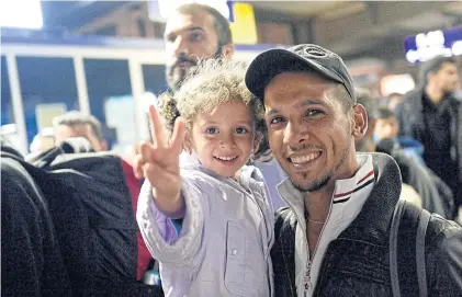  ?? EPA ?? A refugee father and daughter pose for a photo after arriving from Budapest, Hungary, at the main train station in Munich, Germany, on Saturday. EU President Donald Tusk said he would call a special summit on the migration crisis if the bloc could...