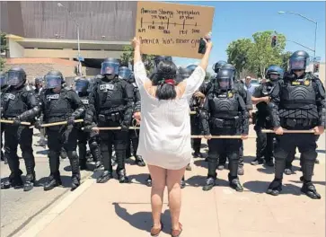  ?? Robin Abcarian Los Angeles Times ?? POLICE IN riot gear face protesters at a Donald Trump rally in Fresno. “We are going to be very patient and wait for these individual­s to leave,” Chief Jerry Dyer said of protesters blocking an intersecti­on.