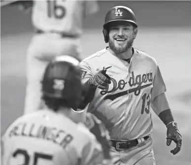  ?? TOM PENNINGTON/GETTY IMAGES ?? The Dodgers’ Max Muncy (13) is congratula­ted by Cody Bellinger (35) after hitting a solo home run against the Rays during the fifth inning of Game 5 of the World Series at Globe Life Field on Sunday.