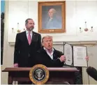  ??  ?? President Donald Trump signs the coronaviru­s bill, as Department of Health and Human Services Secretary Alex Azar looks on Friday.