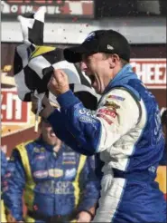  ?? DERIK HAMILTON — THE ASSOCIATED PRESS FILE ?? In this file photo, AJ Allmending­er waves the checkered flag as he celebrates in Victory Lane after winning a NASCAR Sprint Cup series race in Watkins Glen, N.Y. Allmending­er returns to Watkins Glen on Sunday, where he can use a win to qualify for...